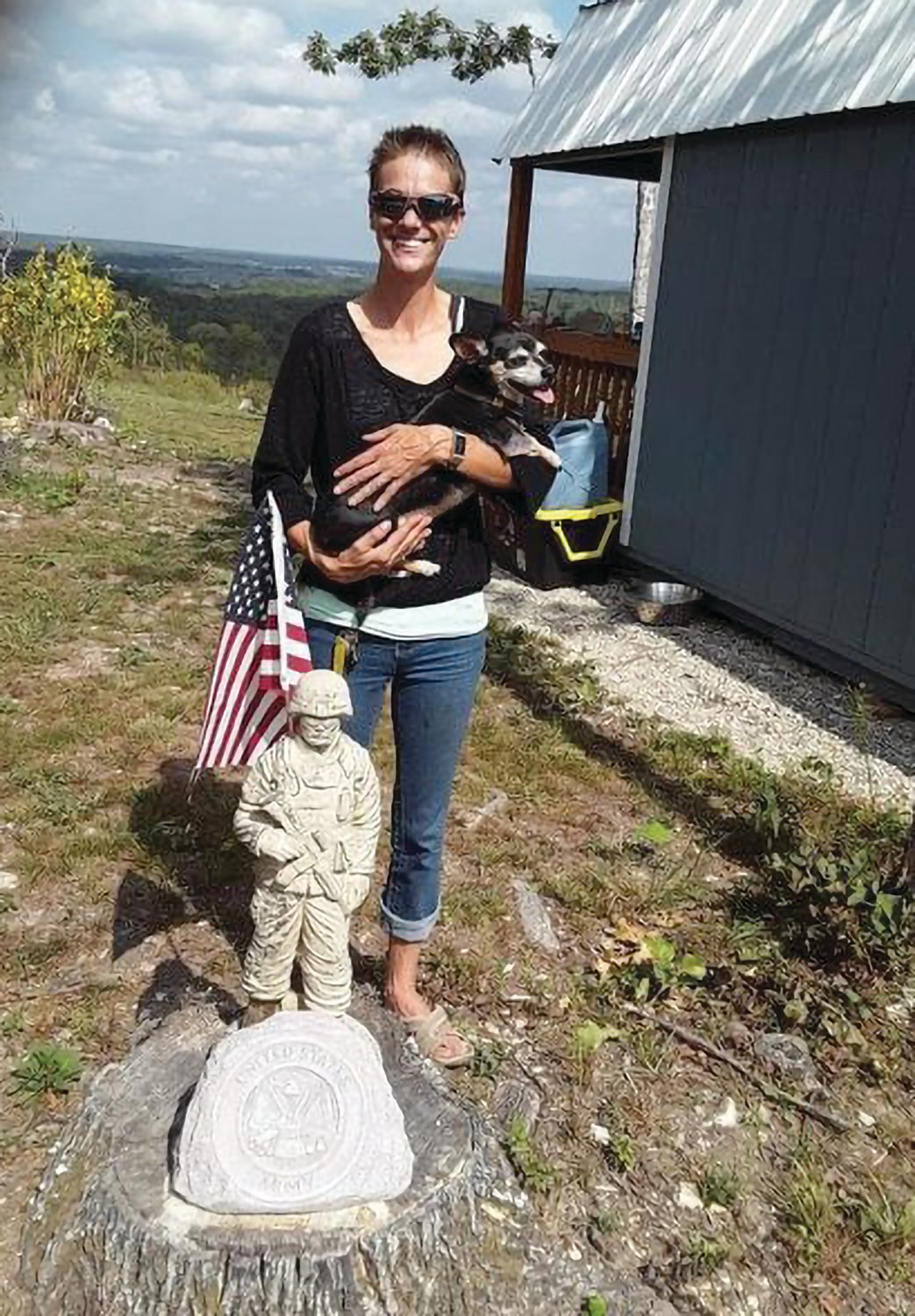 Retired Staff Sergeant Laura Crum with a marker for the United States Army outside her homesteader home in Cedar Gap.
